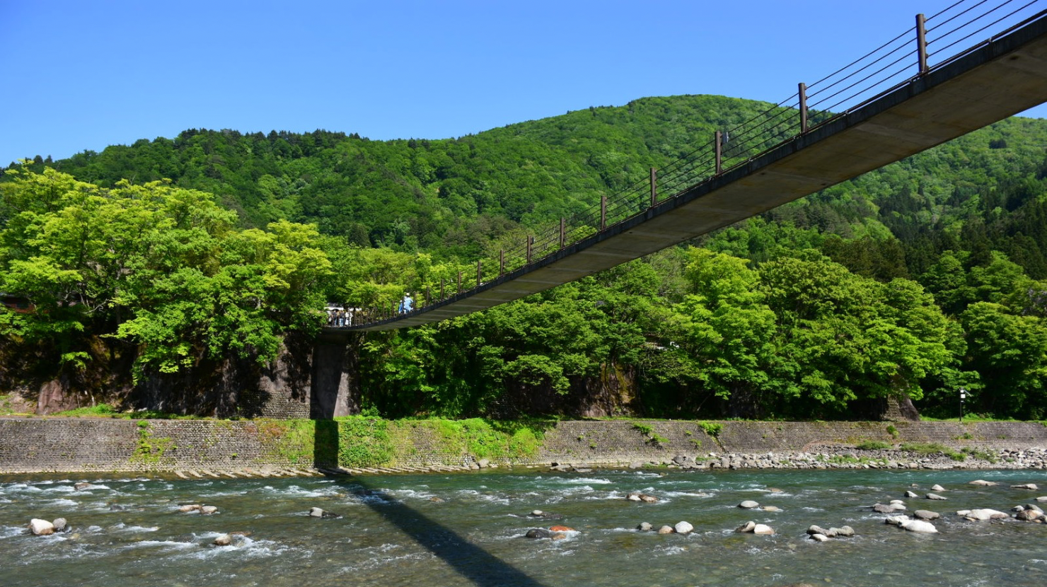 alt="岐阜県白川郷集落へ渡る吊り橋　河川敷でのんびり"
